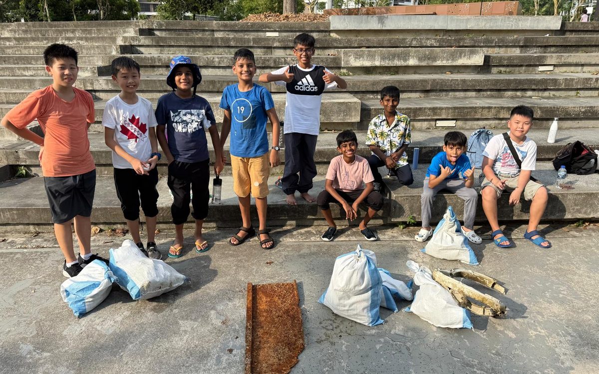 Sharvin and friends after a beach clean-up — collected rubbish in front of them on the steps